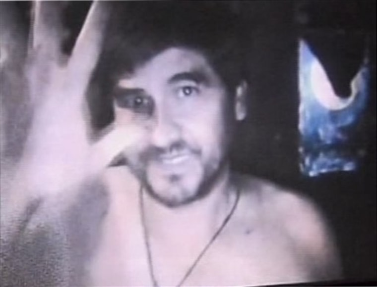 An image from a video released by Chilean television on Thursday shows one of the trapped miners in the underground chamber waving at the camera.